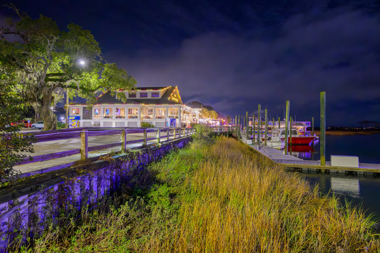Restaurants and cafes with holiday lights illuminate the waterfront at night