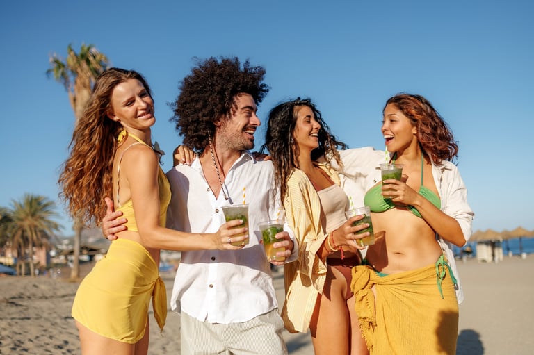 Multiethnic friends enjoying summer vacation on beach with drinks