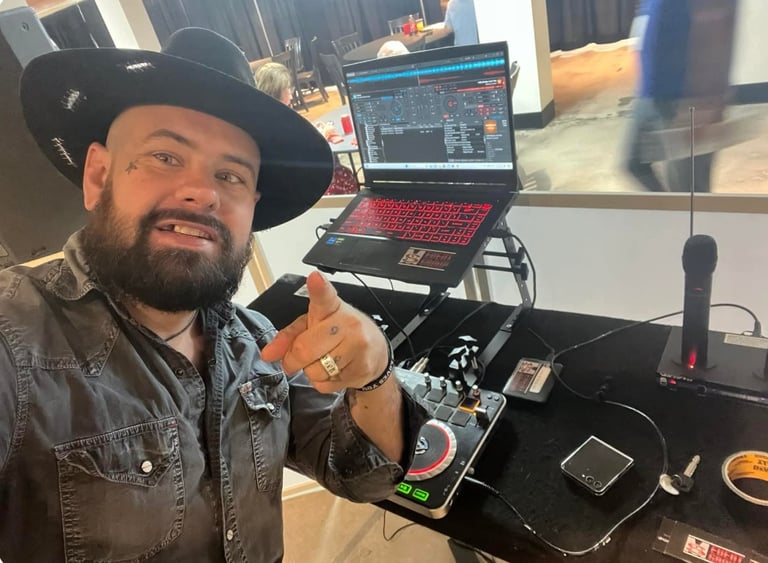Ed, DJ Rusted Saint, in cowboy hat and denim shirt, behind his DJ equipment at a real event