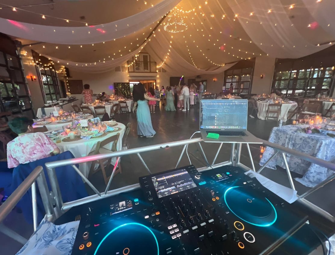 DJ booth with turntables set up at a Corner Stone event, string lights overhead